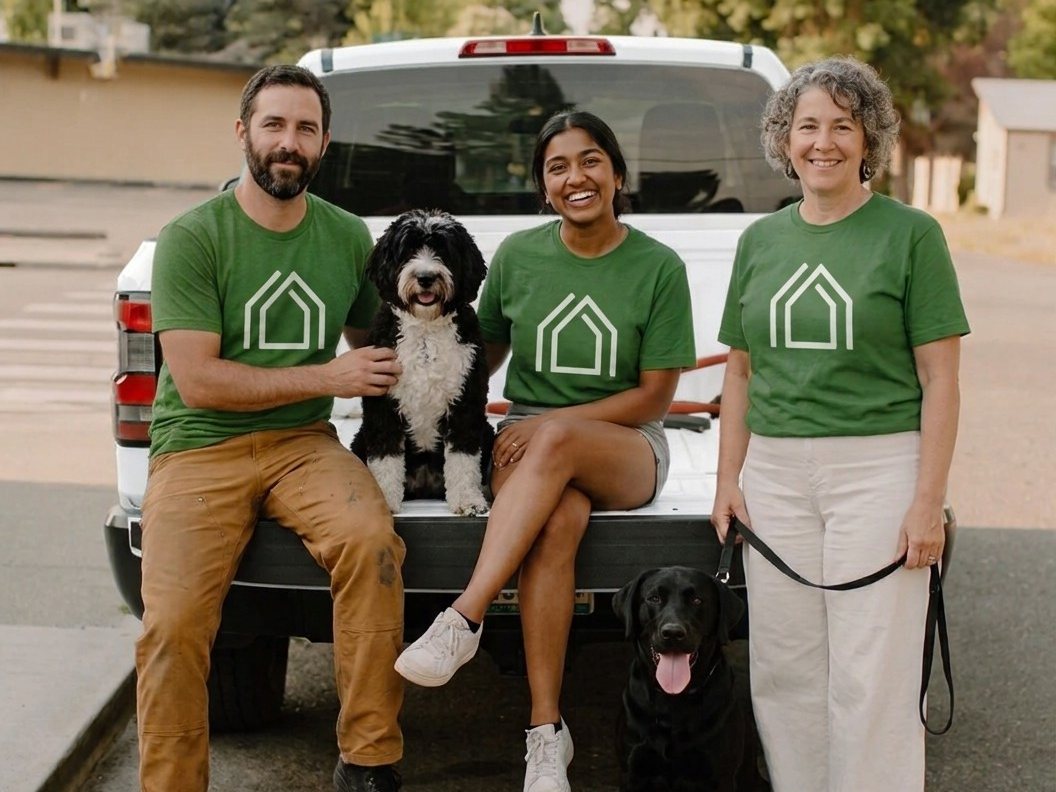 The Bark and Scoop team in green Bark and Scoop shirts at the back of a white pickup truck, with their dogs Max and Mary.